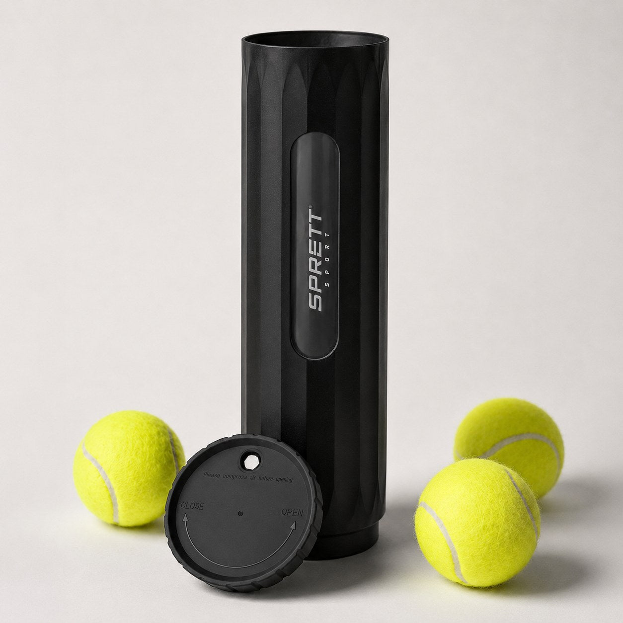 SprettBoks med lokket av, lent mot boksen, og tre tennisballer rundt
